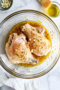 This image shows split chicken breast being coated with olive oil and minced garlic, ensuring a juicy, tender texture and enhancing the flavor before roasting.