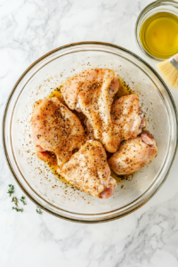 This image shows raw split chicken breasts being coated with olive oil, seasonings, and spices, ensuring a flavorful and juicy result after roasting.