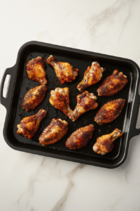 This image shows chicken wings being broiled to a golden-brown color, locking in flavor and crisping up the skin before slow cooking.