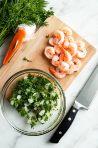 This image shows fresh herbs and garlic being chopped, adding fragrant flavor to the Cheesy Shrimp Tea Sandwich filling.