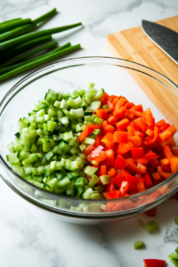 This image shows fresh vegetables, including bell peppers and spinach, being chopped on a cutting board, ready to be mixed into the muffin batter for added flavor and nutrition.