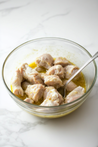 This image shows chicken pieces being coated with a yogurt and spice marinade, allowing them to absorb deep flavors and become tender before cooking.