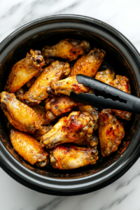 crispy-broiled-wings-being-placed-into-a-slow-cooker-for-further-cooking