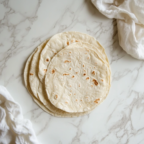 flour-tortillas-on-a-white-marble-slab-ready-to-be-stuffed-with-filling