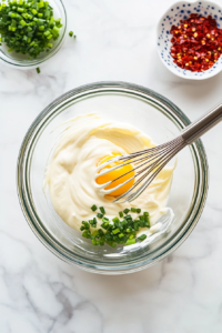 This image shows tender, fresh crab meat being gently folded into the wet ingredients, ensuring the mixture stays light and full of delicate seafood flavor.