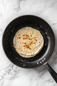 placing-the-rolled-tortilla-onto-the-hot-skillet-for-cooking