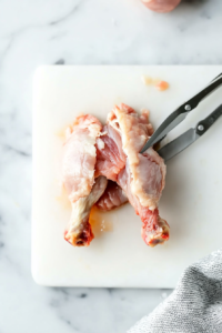 This image shows the meat being pushed upward on the chicken leg, with the joint removed, forming the lollipop shape.