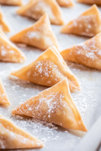 This image shows fingers pressing the edges of a wonton wrapper, sealing it tightly to prevent any filling from leaking during cooking.