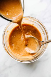 This image shows the freshly made crab cake sauce being carefully poured into a glass jar with an airtight lid, ensuring freshness and easy storage in the refrigerator for future use.