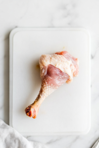 This image shows the cartilage being trimmed off the bone, ensuring the lollipop chicken stands upright for even baking.