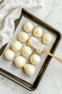 This image shows egg puffs brushed with egg wash, arranged in neat rows on a parchment-lined baking tray, ready to be baked to crispy golden perfection.